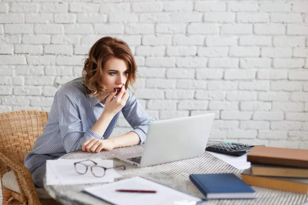 Surprised businesswoman looking at laptop pc, astonished woman with shocked face and open mouth