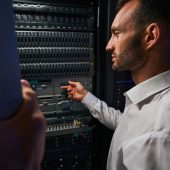 Close up portrait of handsome Caucasian it engineer standing near the rack server