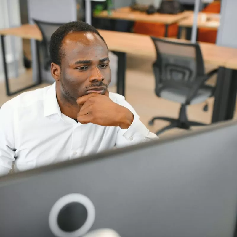 African American trader works at computer with displayed real-time stocks