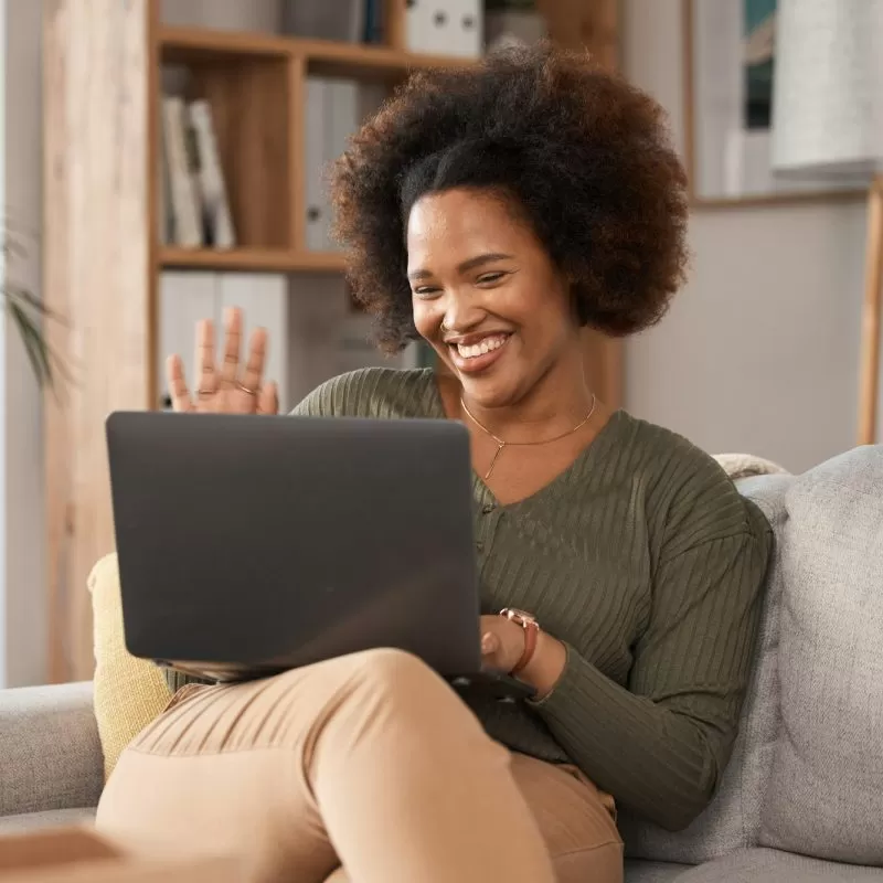 Happy black woman, laptop and hello on video call, internet communication and voip chat for remote