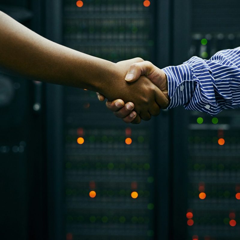 Paired up for professional IT service. Cropped shot of two men shaking hands in a data center.