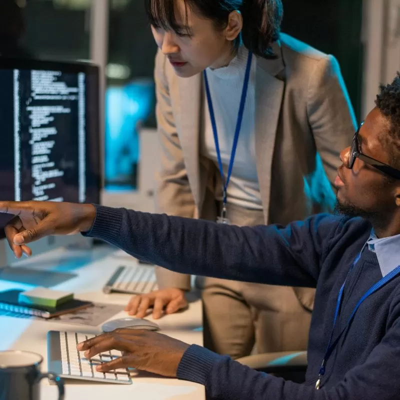 Two young intercultural colleagues discussing coded data